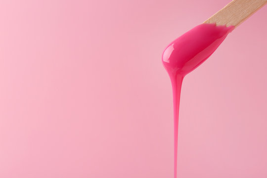 liquid wax for pink depilation drains from the stick. The concept of  depilation, waxing, smooth skin without hair. Stock Photo